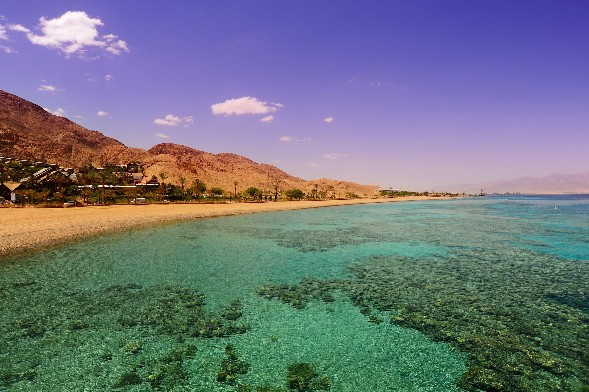 Egyptian coastal city with crystal clear waters, sandy beach, desert mountains and buildings along the Red Sea