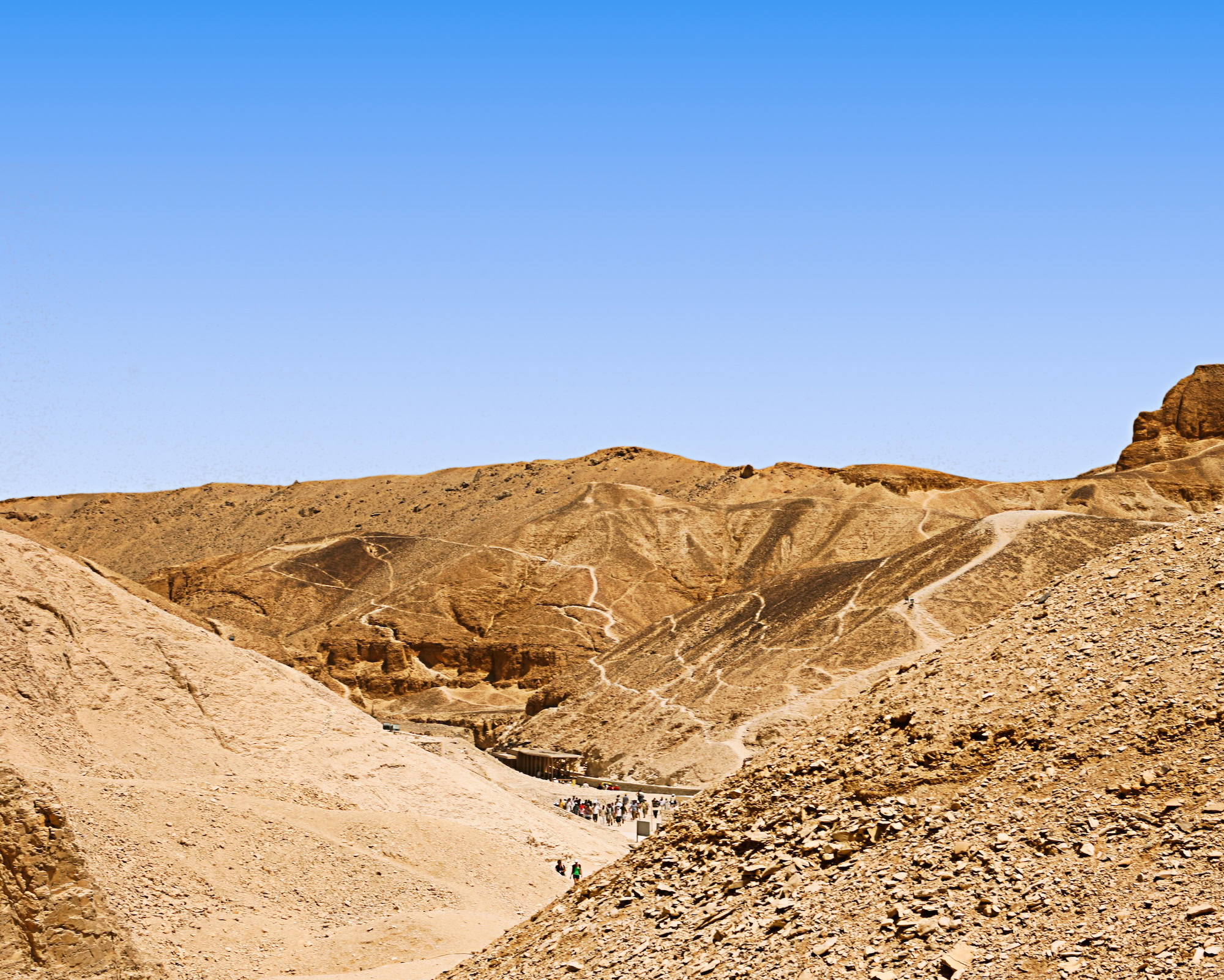 Tourists exploring the Valley of the Kings desert landscape with limestone cliffs