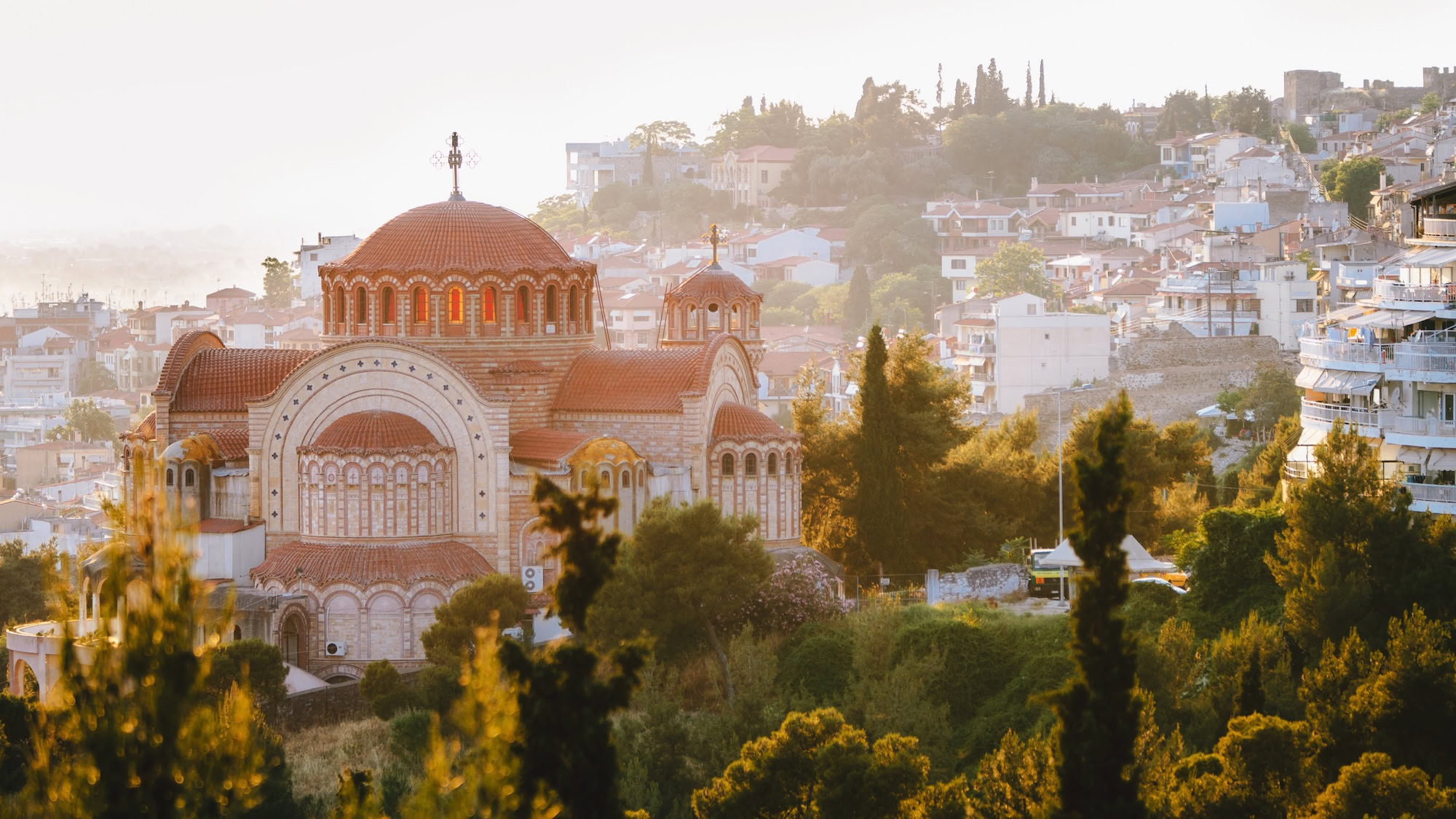 Igreja bizantina ortodoxa com cúpulas vermelhas em uma encosta na Grécia