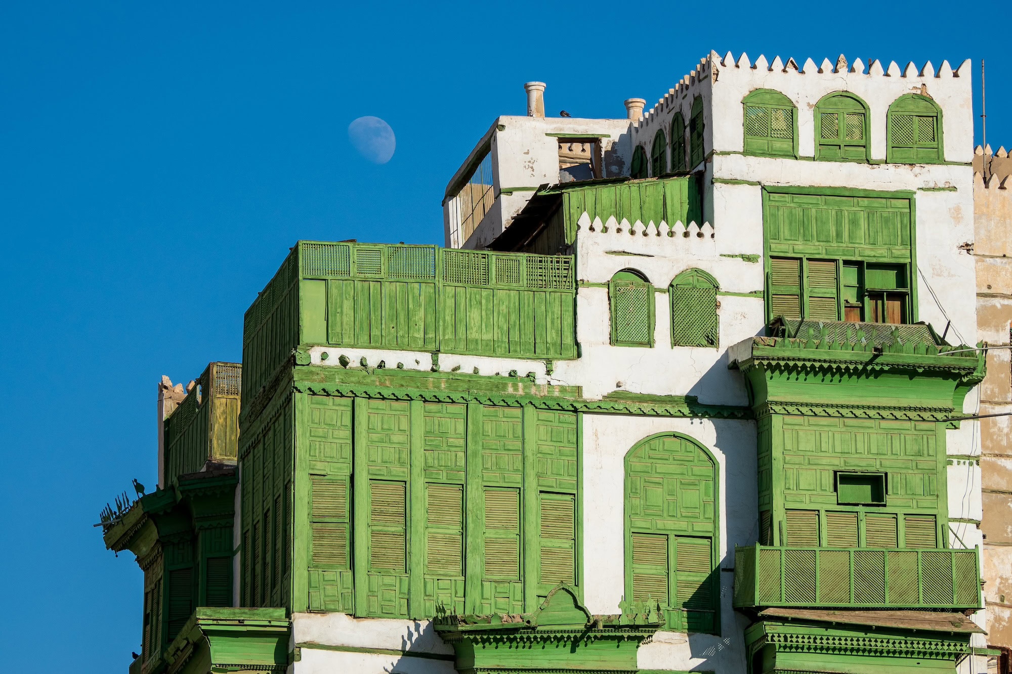 Traditional multi-story building in Historic Jeddah with wooden balconies and shutters under moonlight