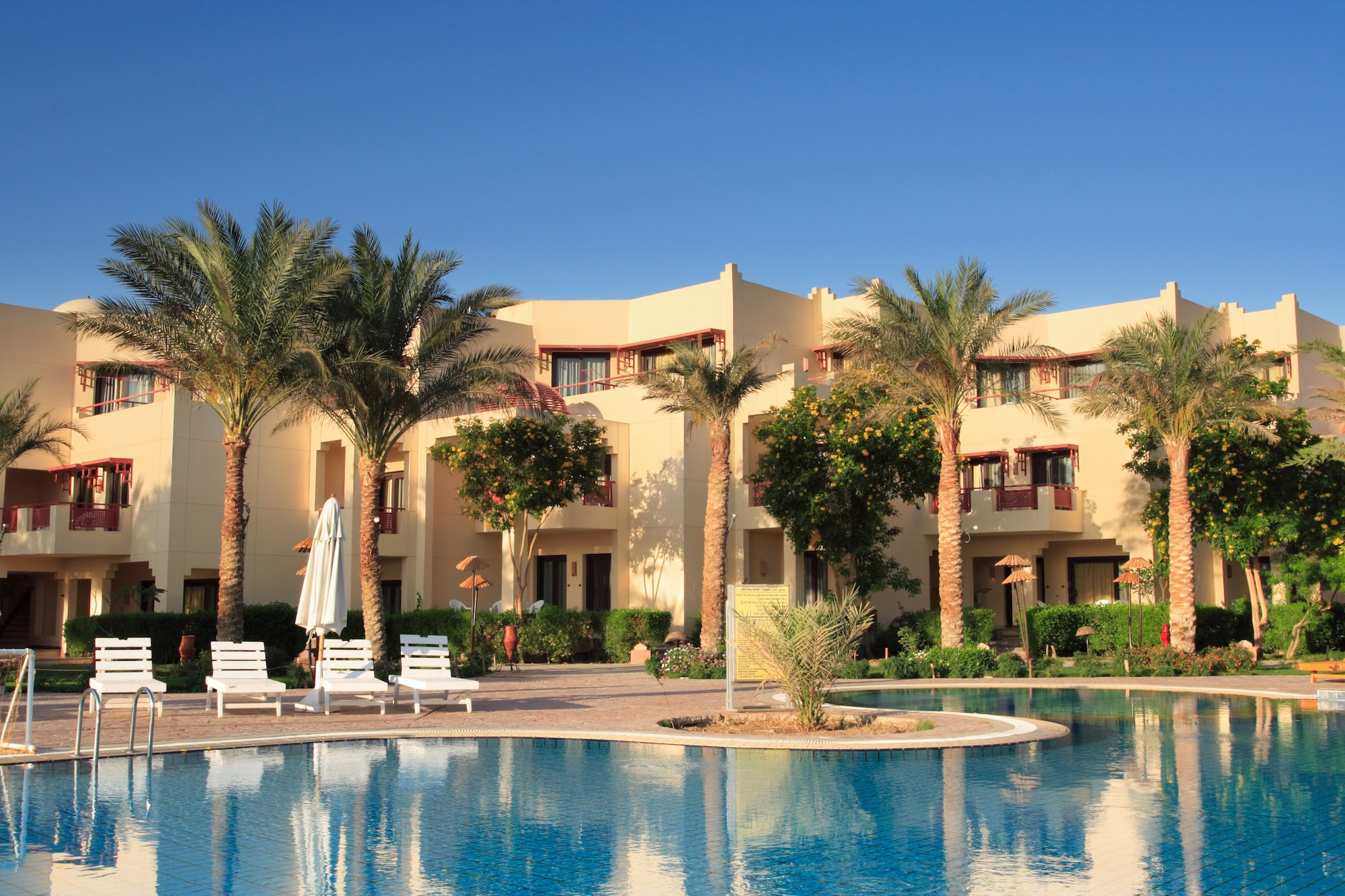 Luxury resort swimming pool complex in Hurghada with palm trees and beige buildings