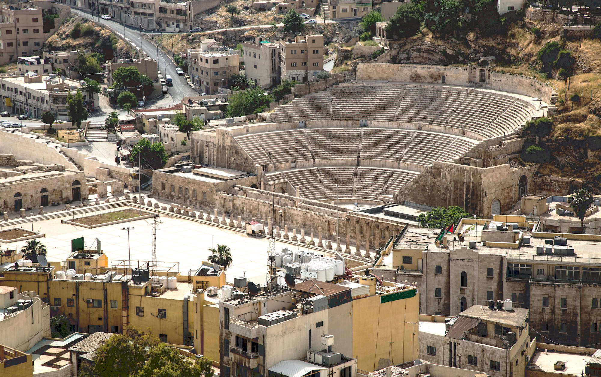 Aerial view of Roman Theater amphitheater surrounded by modern Amman cityscape