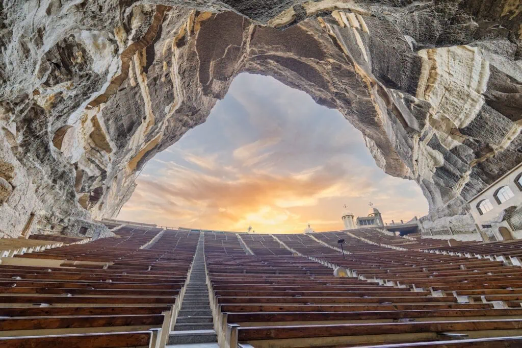 The large rock-carved interior with stepped seating and carved stone walls inside Saint Simon the Tanner Cathedral, Cairo