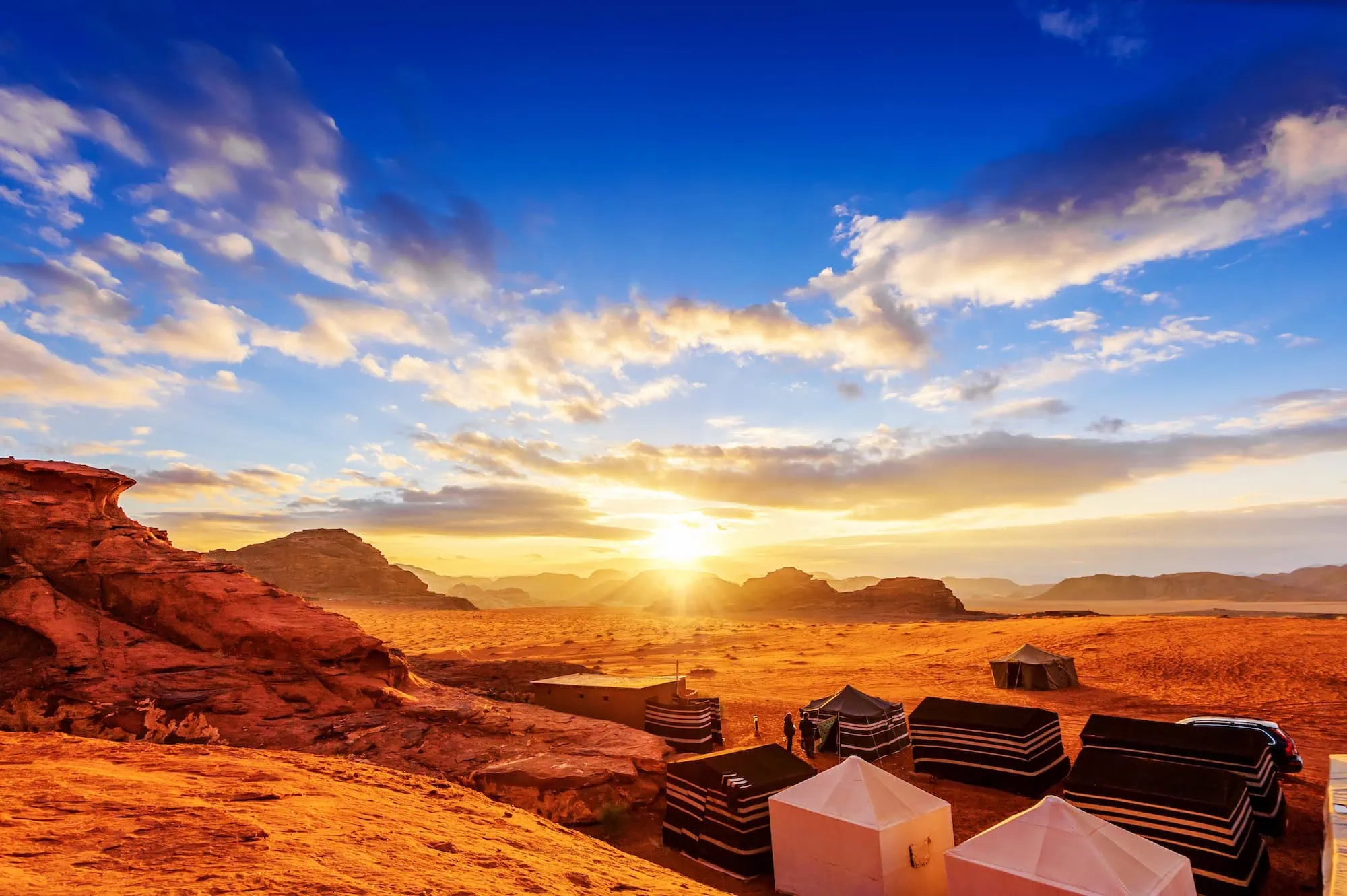 Desert camp with black and white tents at sunset in Wadi Rum desert