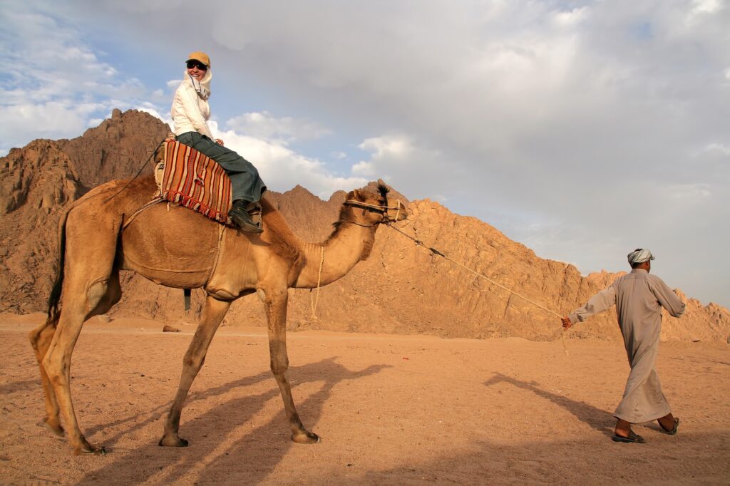 Desert camel ride showing a woman riding a camel across open sandy terrain, Hurghada