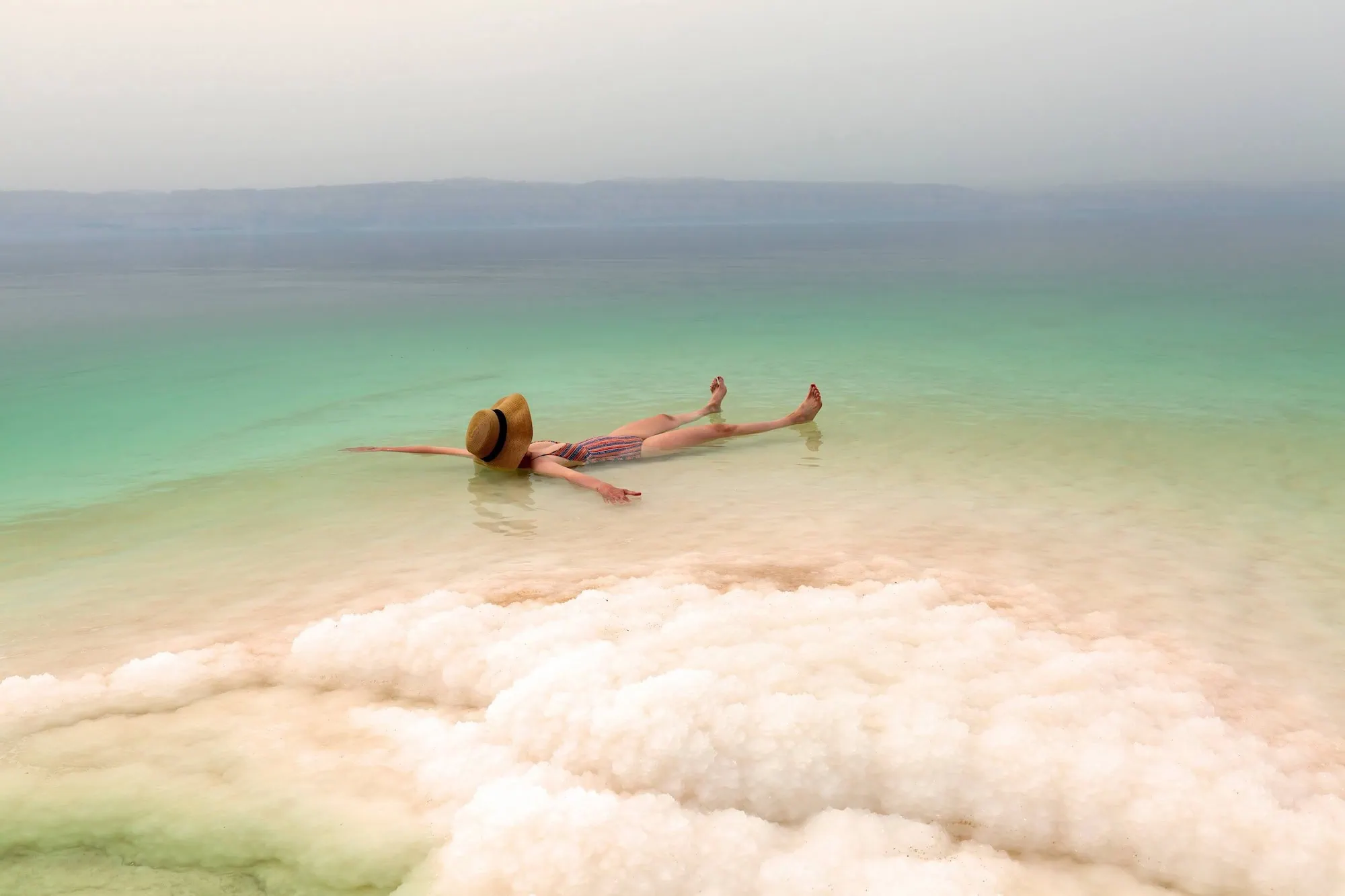 Woman in striped swimsuit floating effortlessly in the salty waters of the Dead Sea