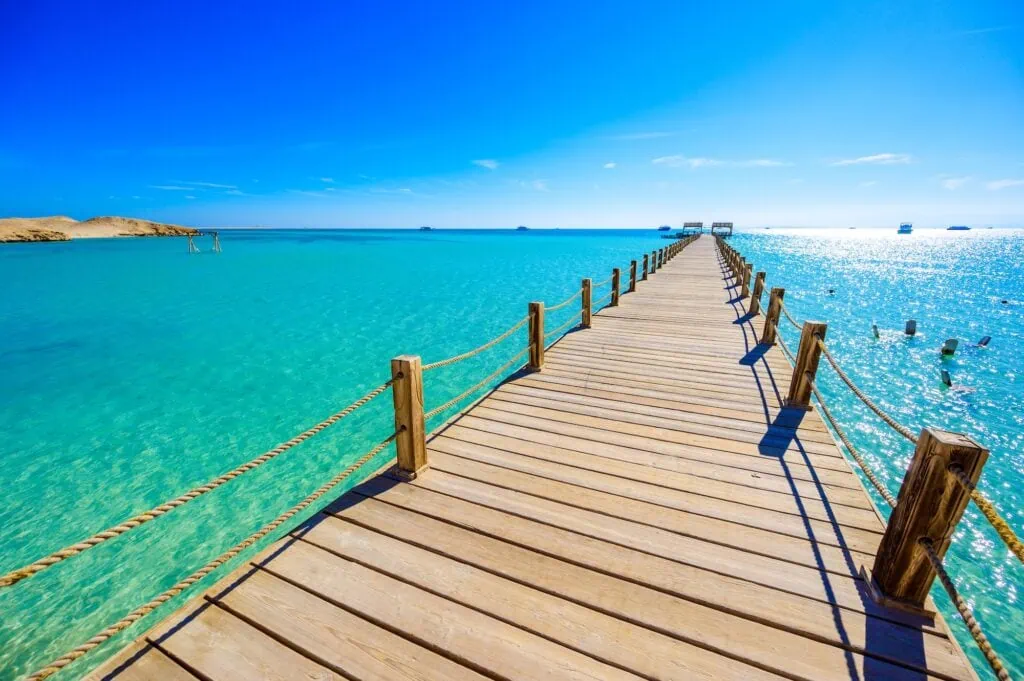 Wooden pier extending over clear turquoise water at Orange Bay Beach on Giftun Island, Hurghada