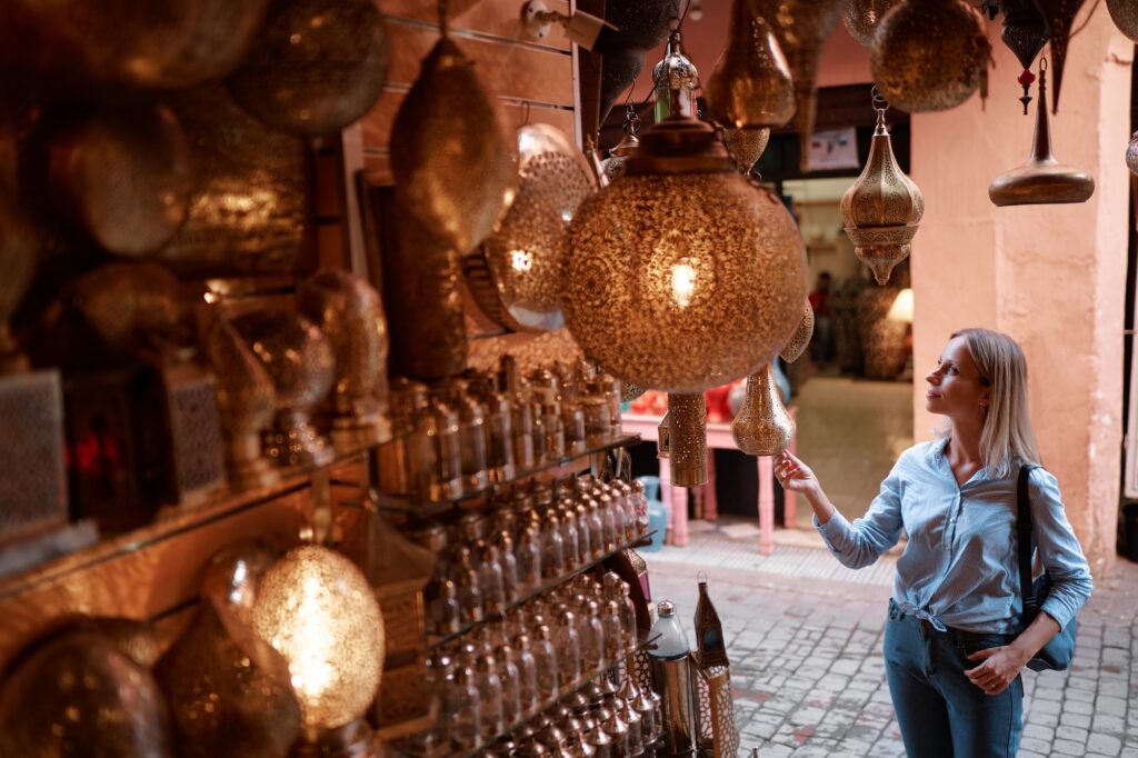 Young traveling woman with choose presents in copper souvenir handicraft shop in Morocco