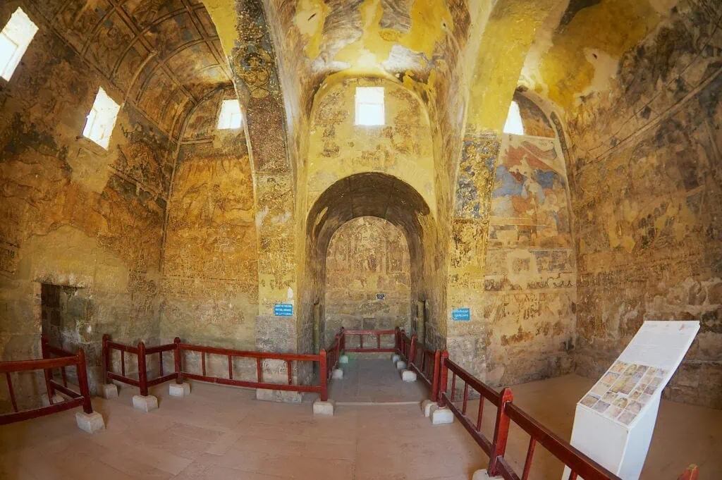 Interior view of mural-covered walls and decorated ceiling inside Qasr Amra, Zarqa