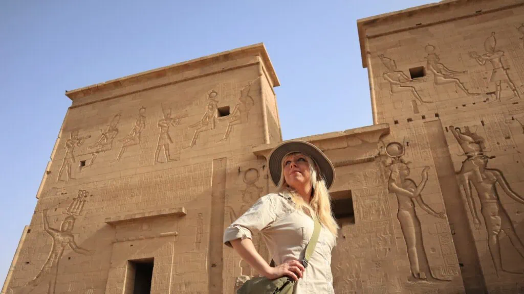 Tourist standing before the monumental sandstone pylons and entrance reliefs, Temple of Edfu