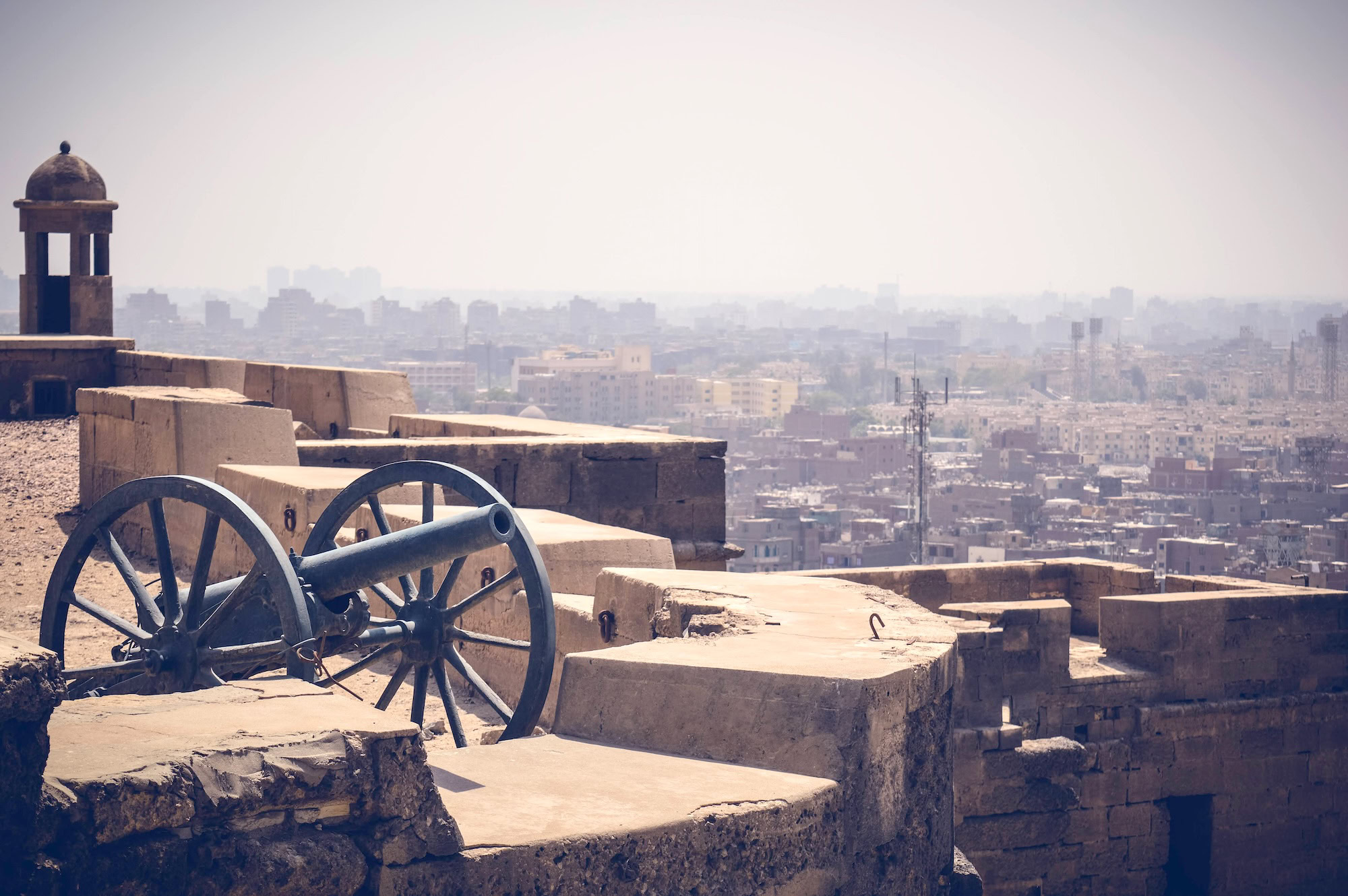 Historical cannon positioned on stone fortifications of Cairo Citadel overlooking cityscape