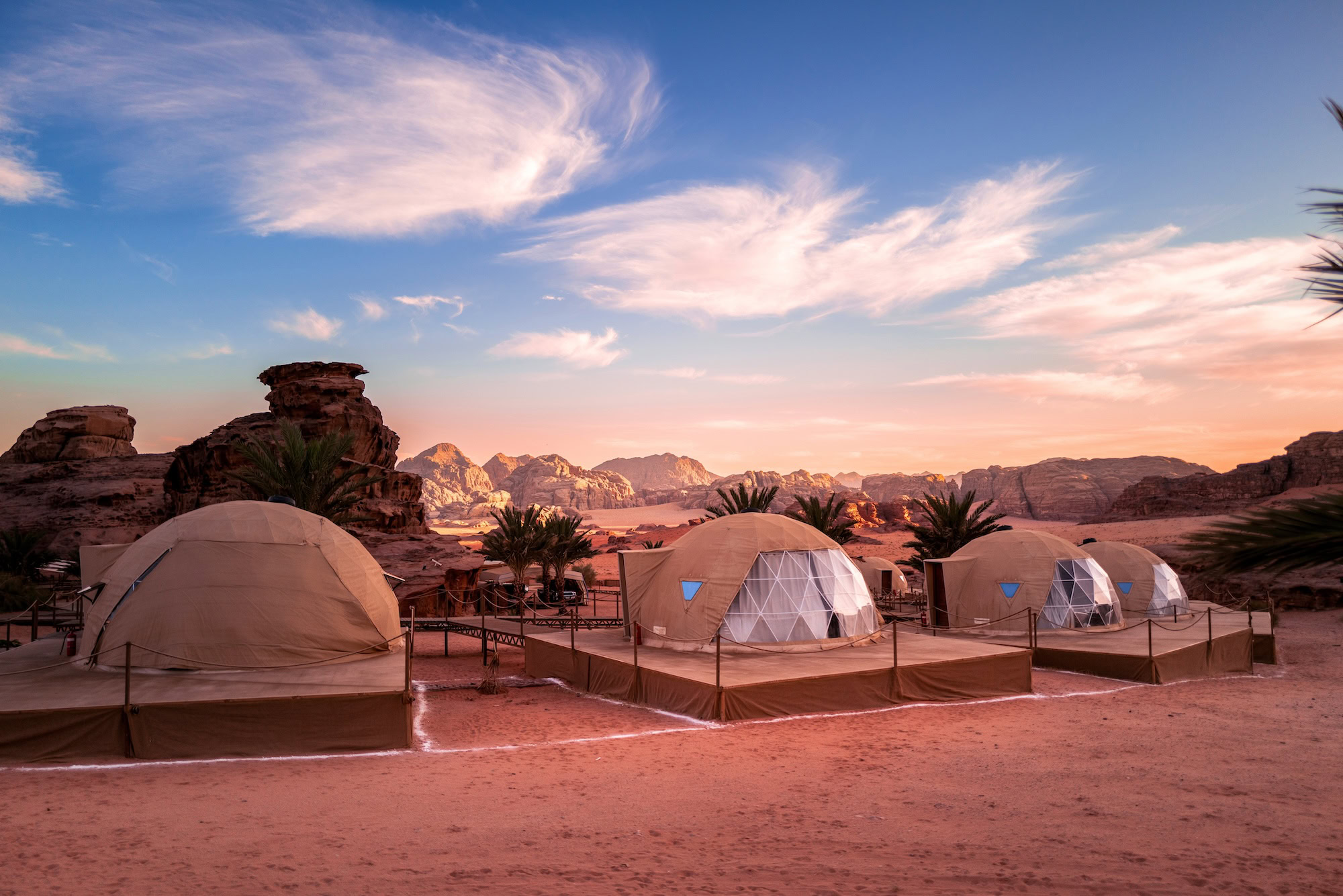 Luxury desert camp with white geodesic tents in Wadi Rum desert at sunset