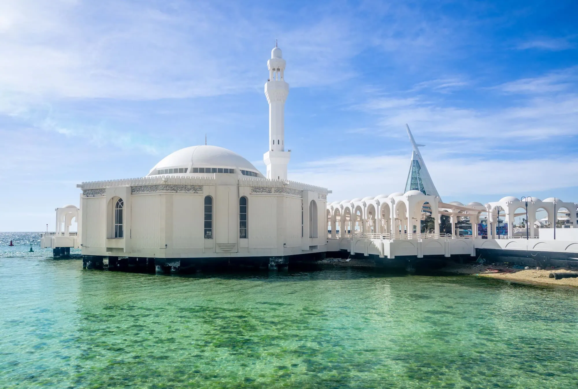 Floating mosque in Jeddah with white dome and minaret built over blue-green water