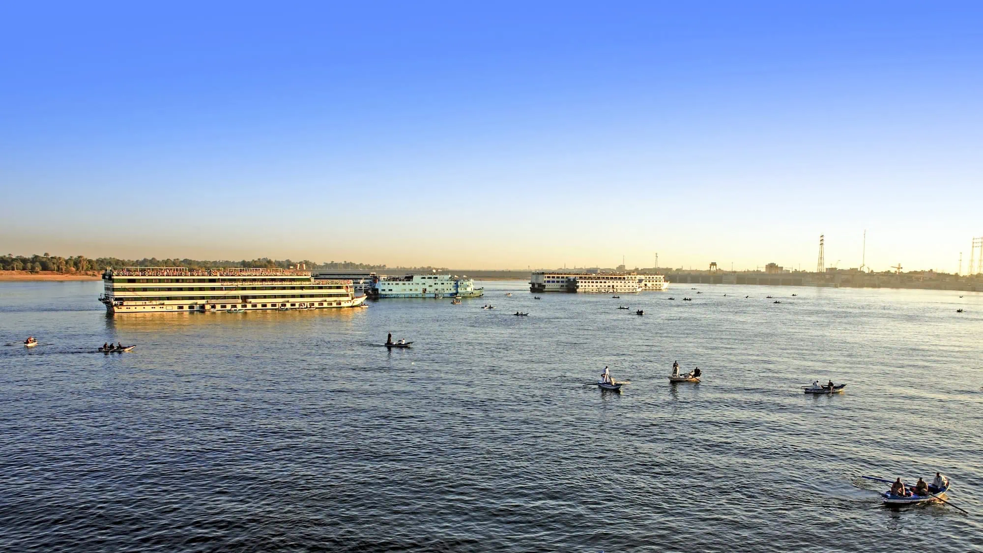 Various Nile River boats including cruise ships and traditional feluccas on calm waters