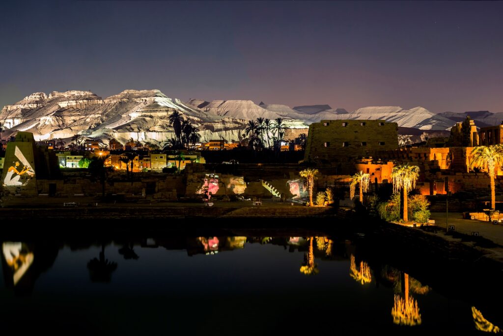 Illuminated ruins and reflections at the Sacred Lake during the Sound and Light show at Karnak Temple