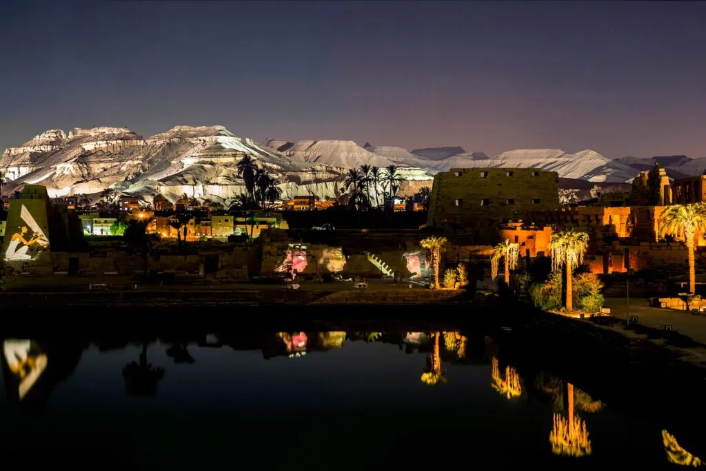 Illuminated ruins and reflections at the Sacred Lake during the Sound and Light show at Karnak Temple