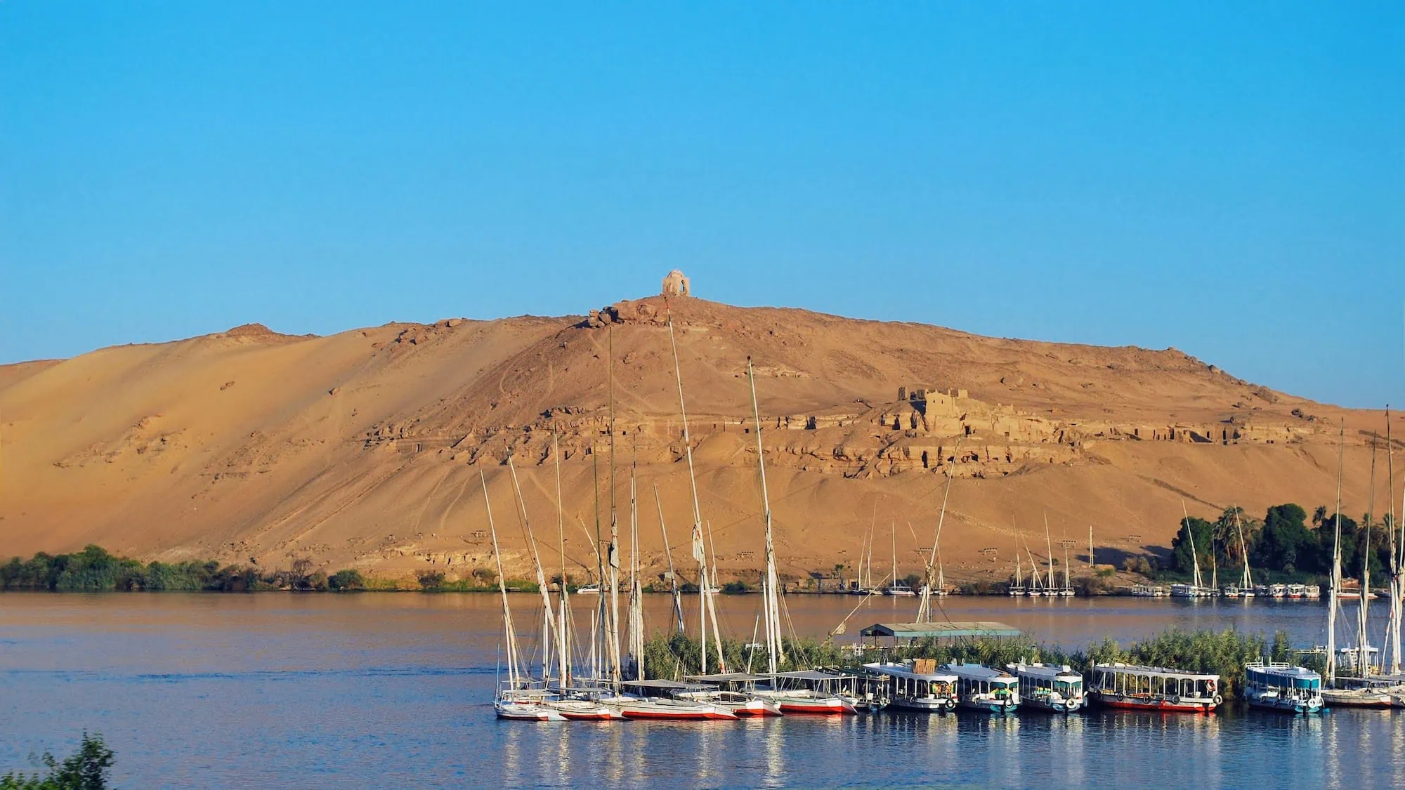 Ancient Egyptian tombs carved into desert hills overlooking the Nile River at Aswan