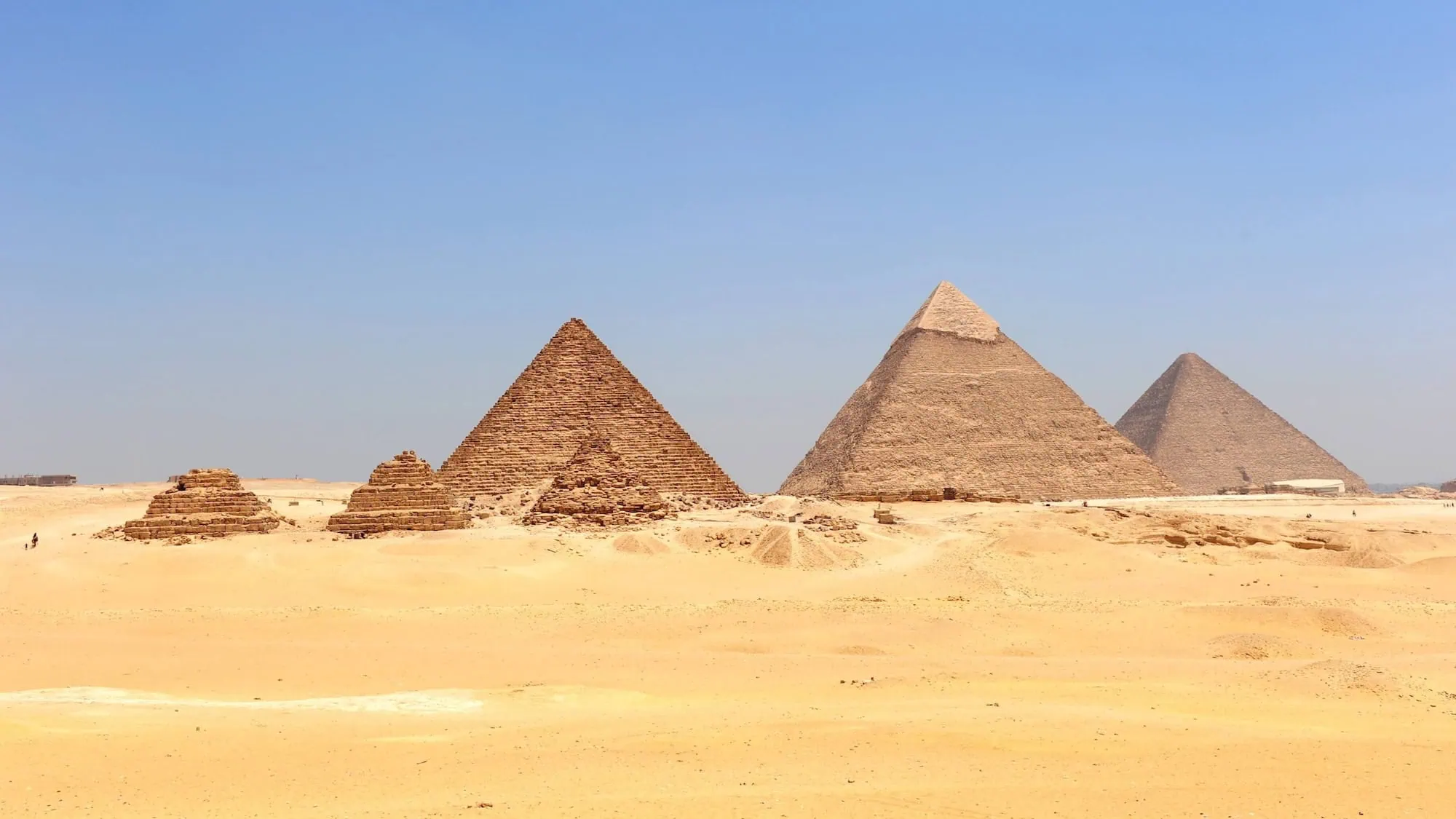 Panoramic view of the three Great Pyramids of Giza against blue sky