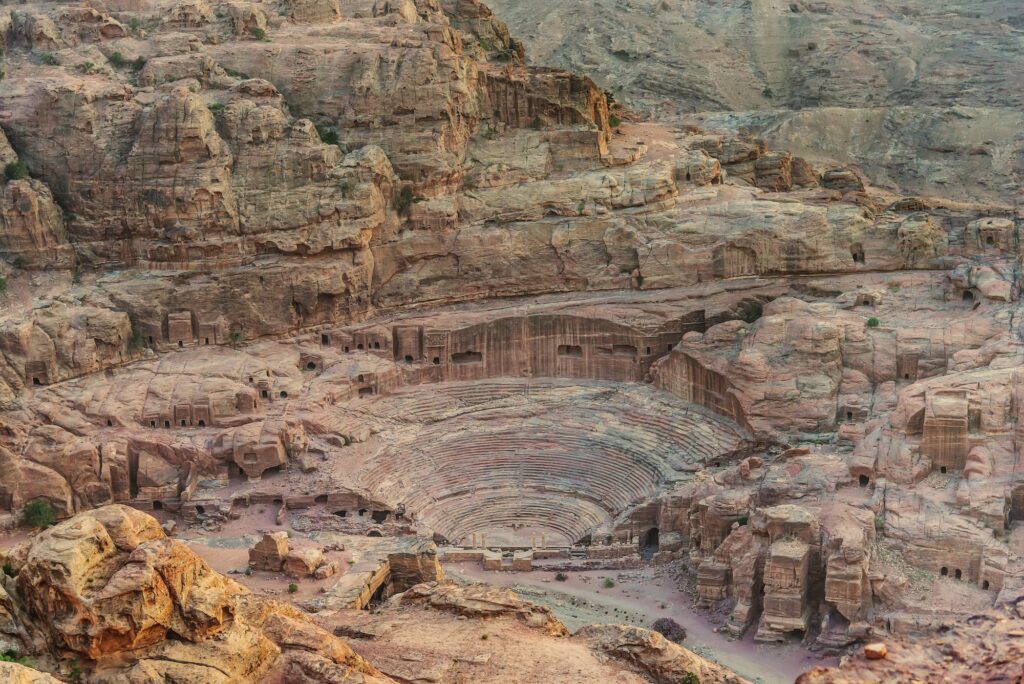 Roman-style theater arena carved into rose-colored rock in the ancient city of Petra, Wadi Musa
