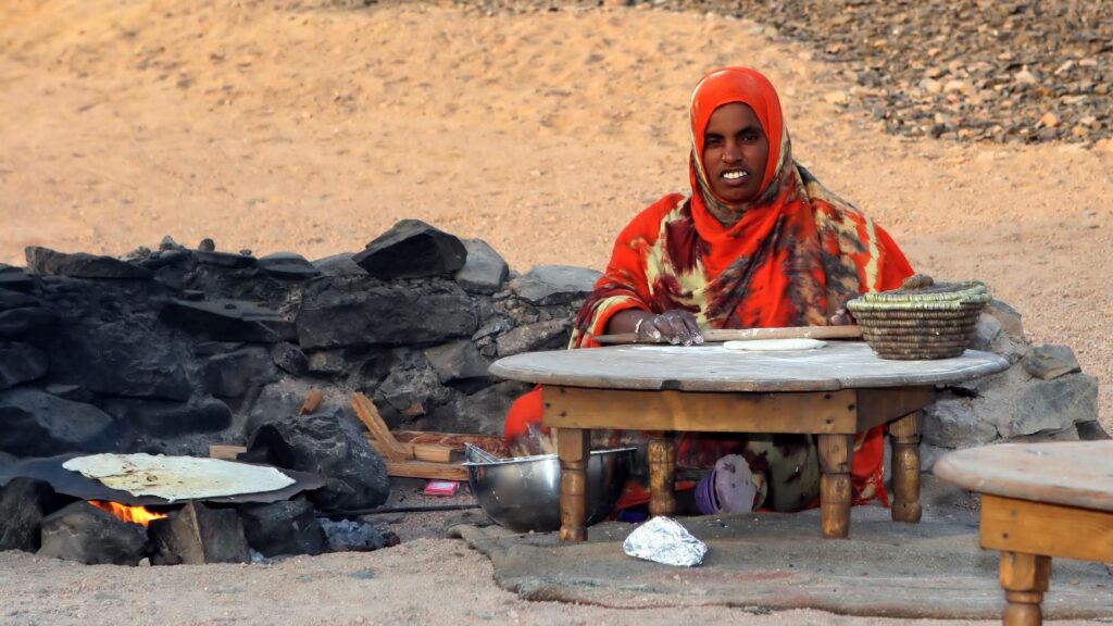 Bedouin woman preparing traditional flat cakes from flour at a desert camp