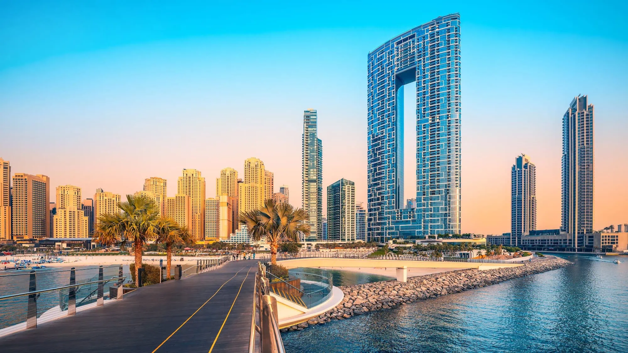 Jumeirah Beach Dubai skyline at sunset with palm trees and boardwalk