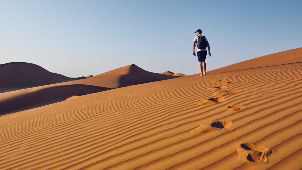 Young backpacker walking along a sandy desert dune
