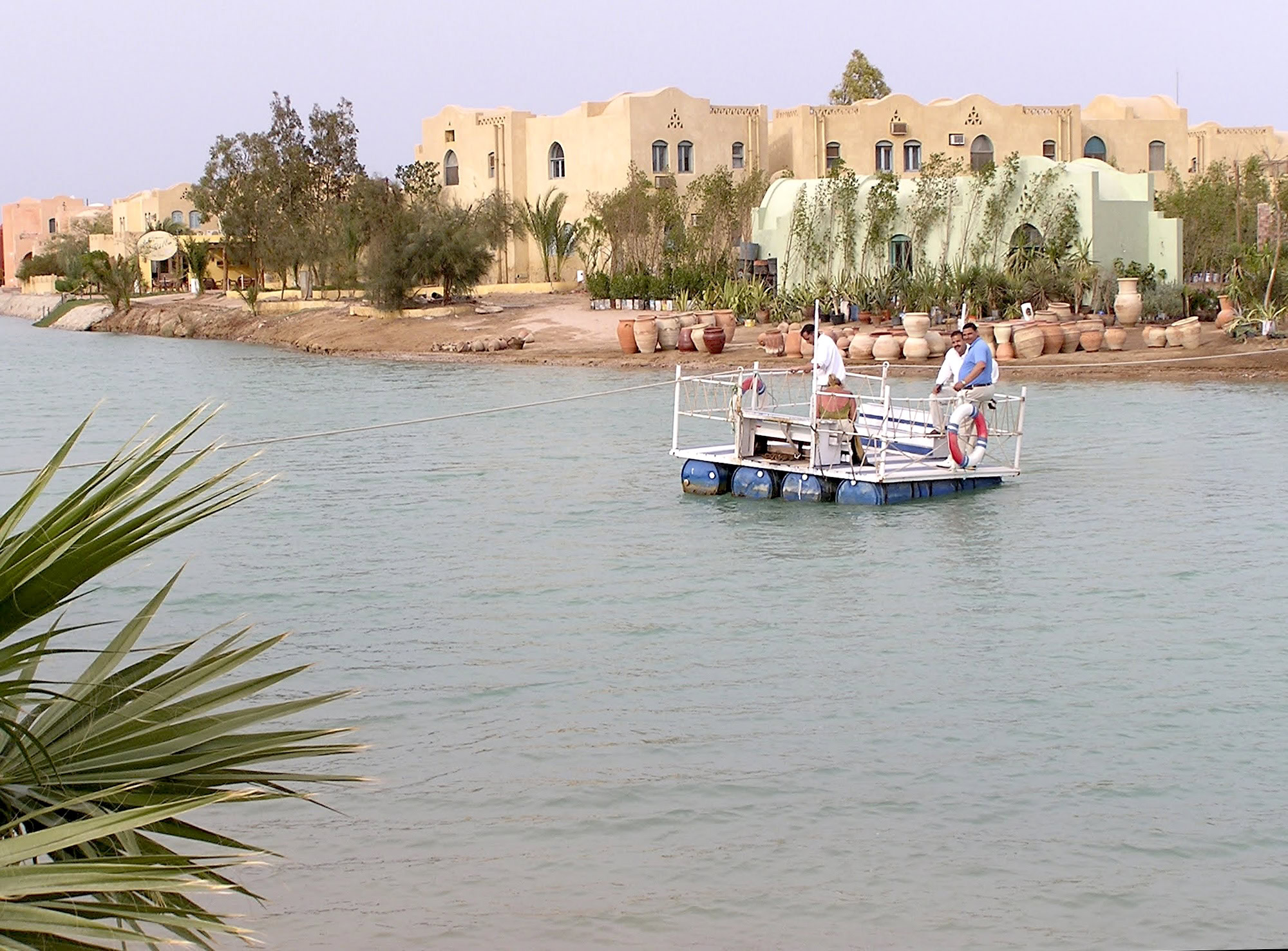 Serene waterfront view of El Gouna's lagoon system with boat, buildings, and palm vegetation