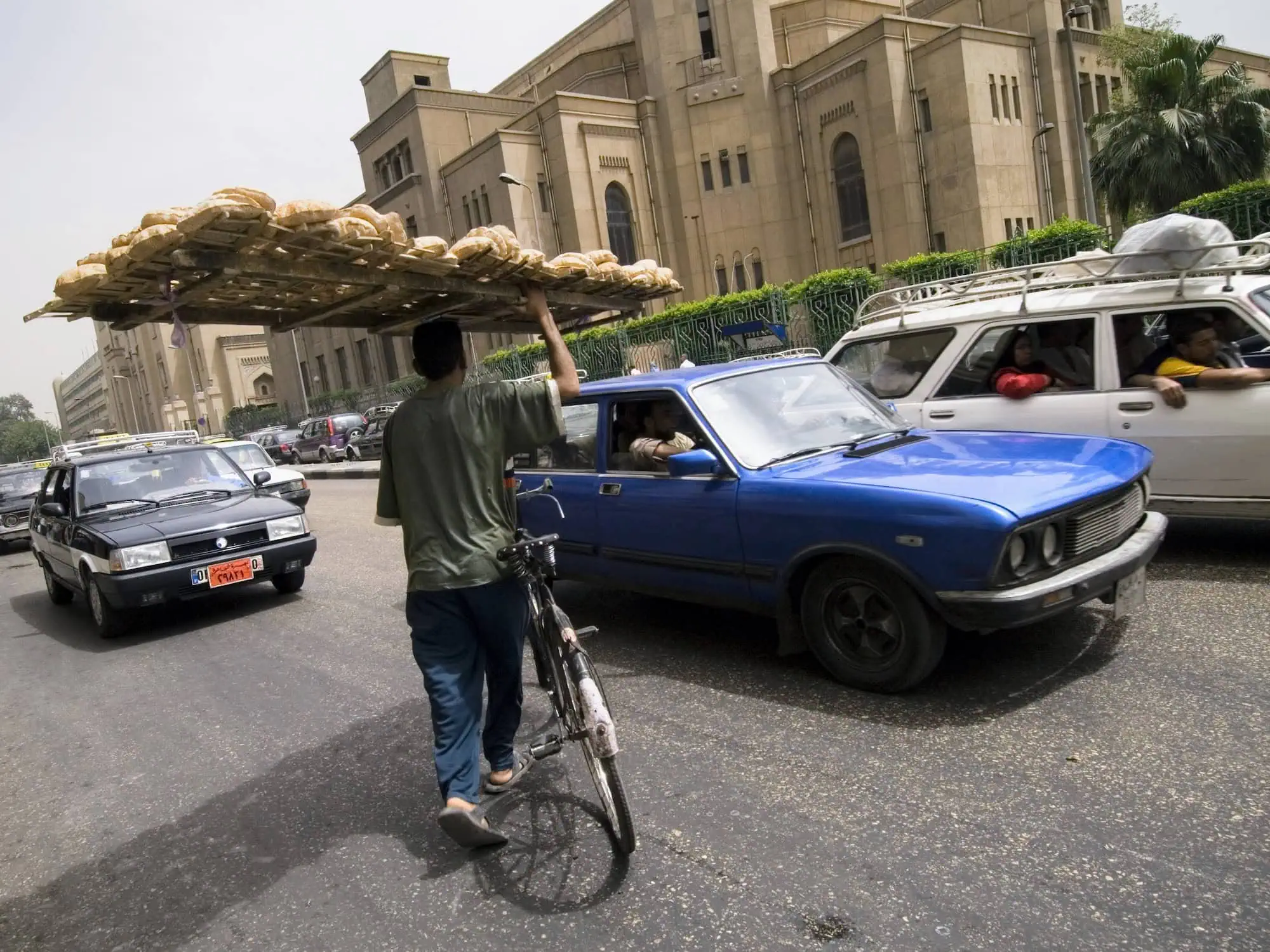 Busy Egyptian street with cars, bread vendor, and government building