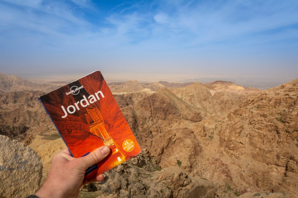travel guide displayed against dramatic desert mountains and sky in the Wadi Rum landscape, Wadi Rum