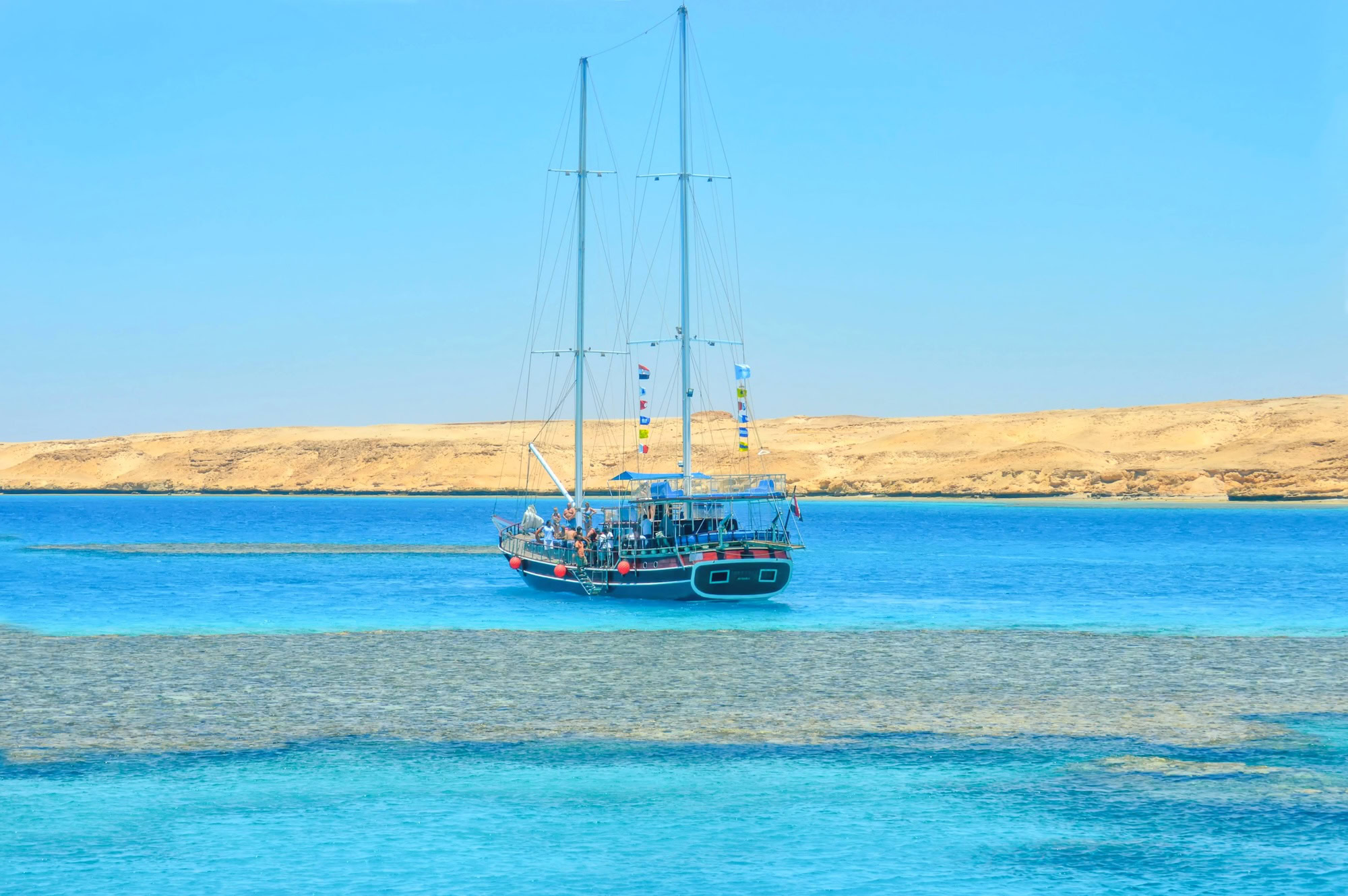 Sailing yacht anchored in crystal clear turquoise waters near coral reef at Tiran Island