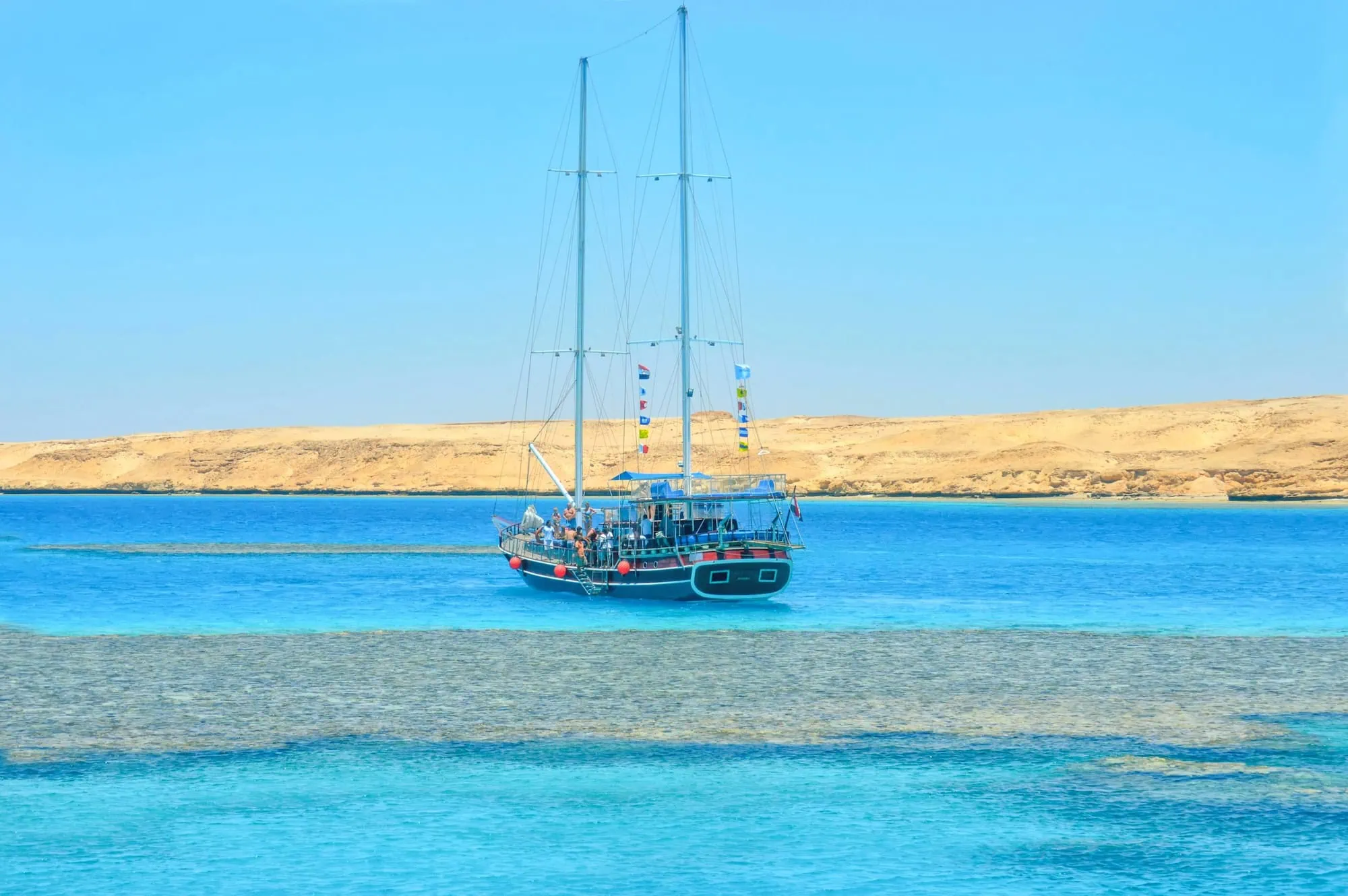 Sailing yacht anchored in crystal clear turquoise waters near coral reef at Tiran Island