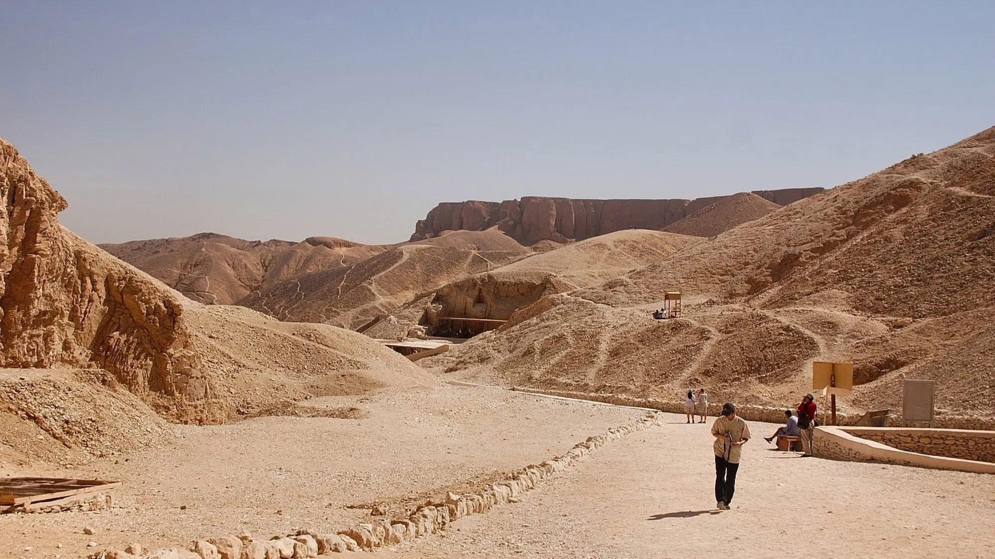Tourists exploring tomb entrances in the Valley of the Kings desert archaeological site
