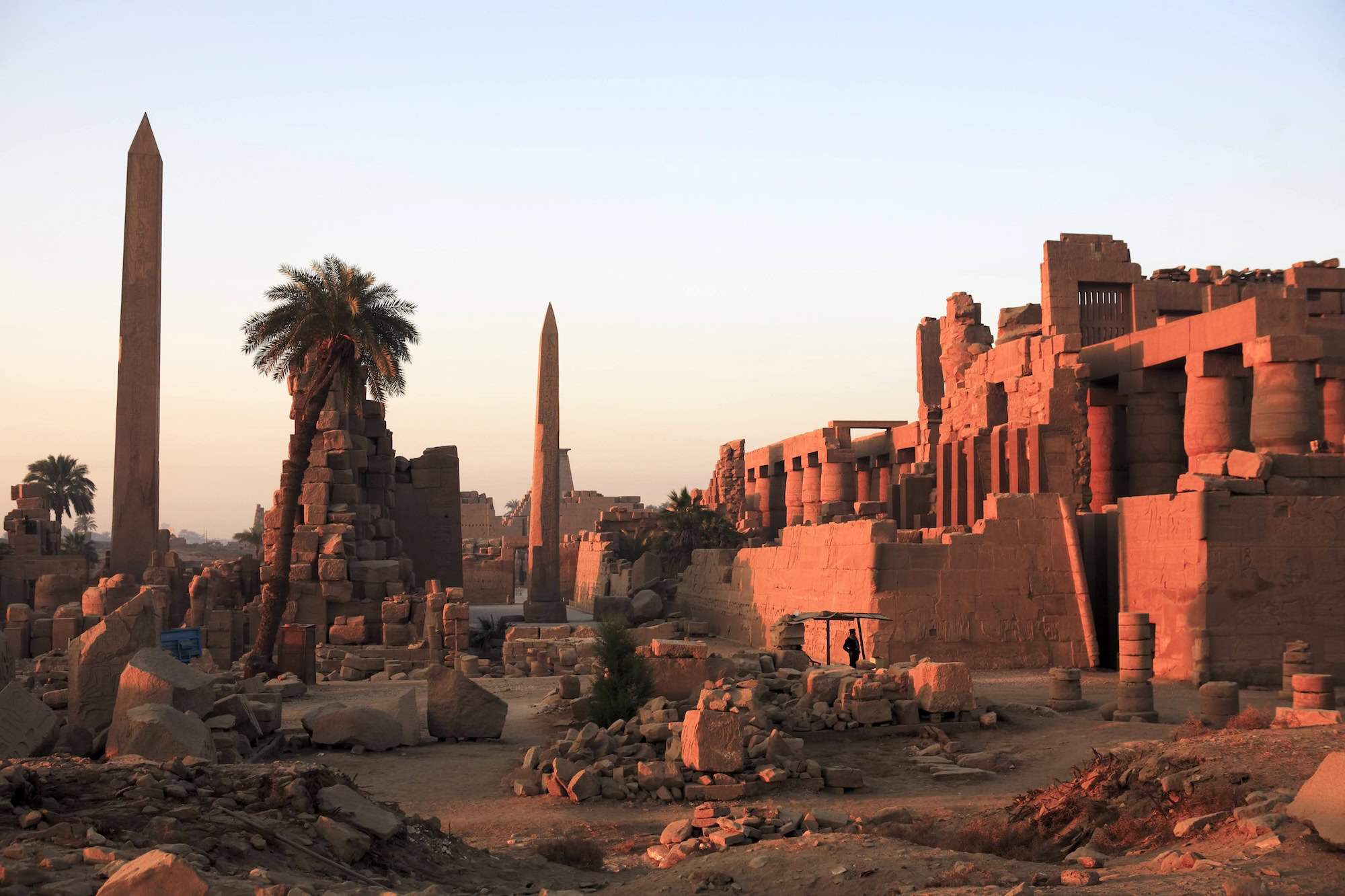 Ancient Egyptian Karnak Temple complex with massive stone columns and obelisks illuminated by golden sunset light