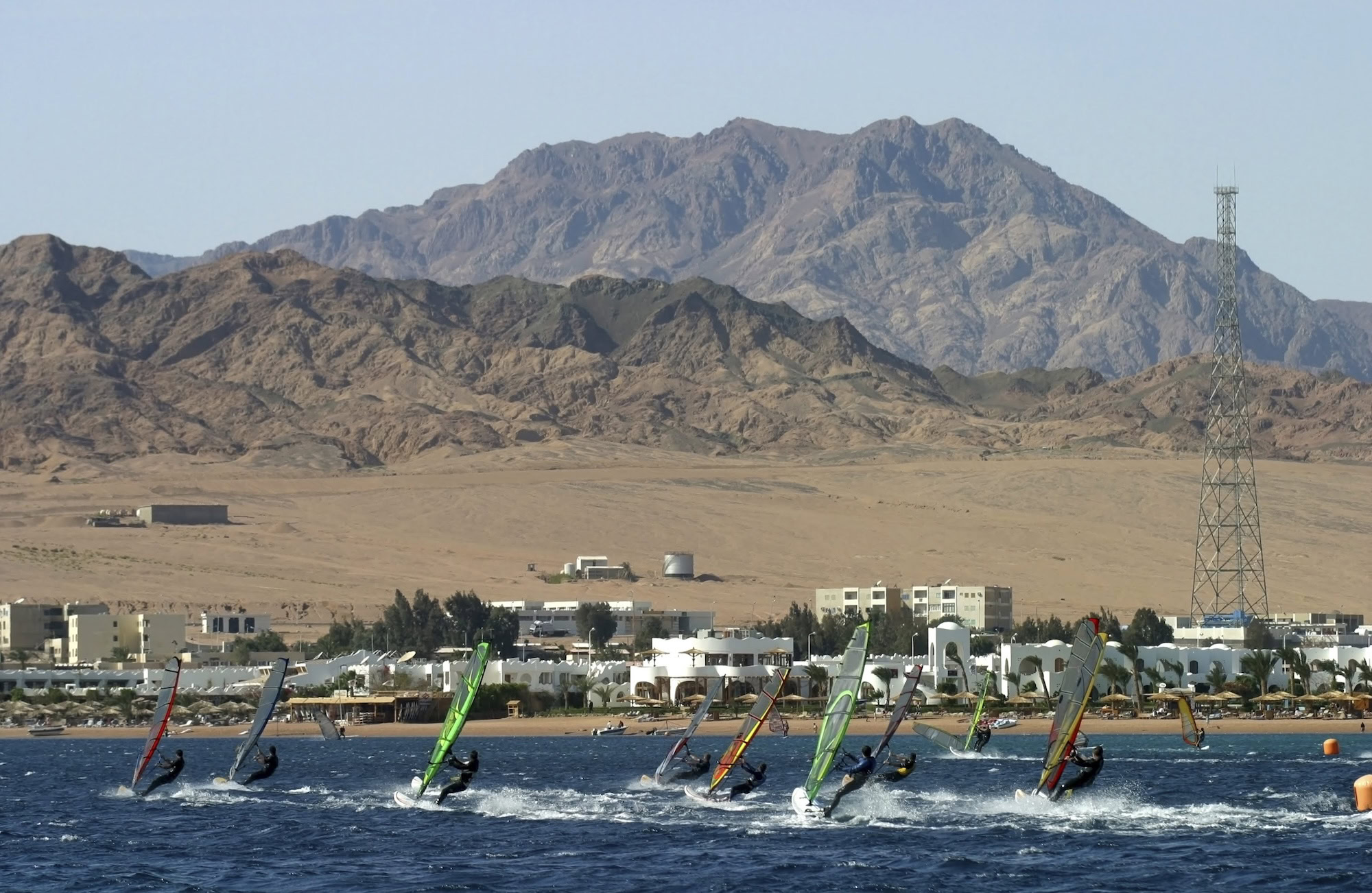 Windsurfers with colorful sails on the Red Sea with desert mountains in background
