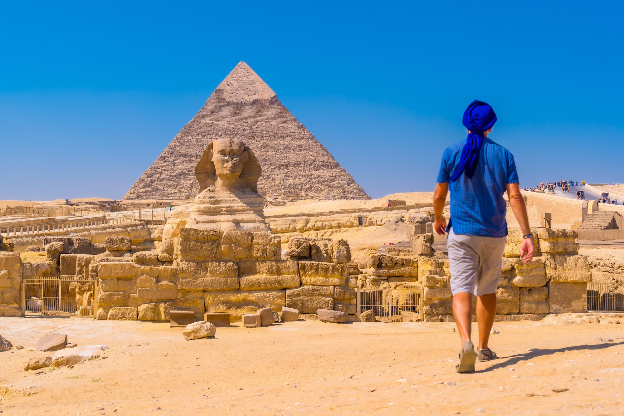 A young man walking towards the Great Sphinx of Giza and in the background the pyramid of Khafre, the pyramids of Giza