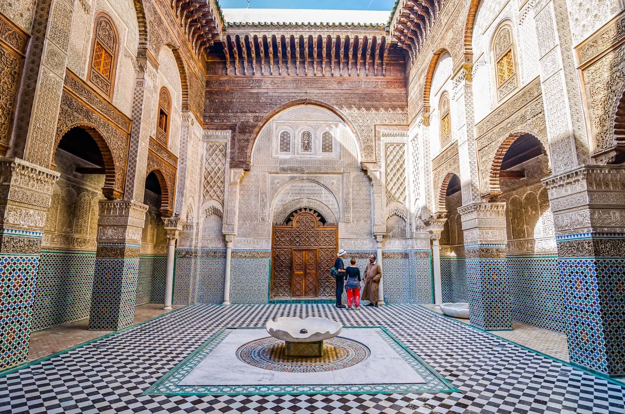 Interior courtyard of Bou Inania Madrasa showing intricate Islamic geometric patterns and mosaic tilework