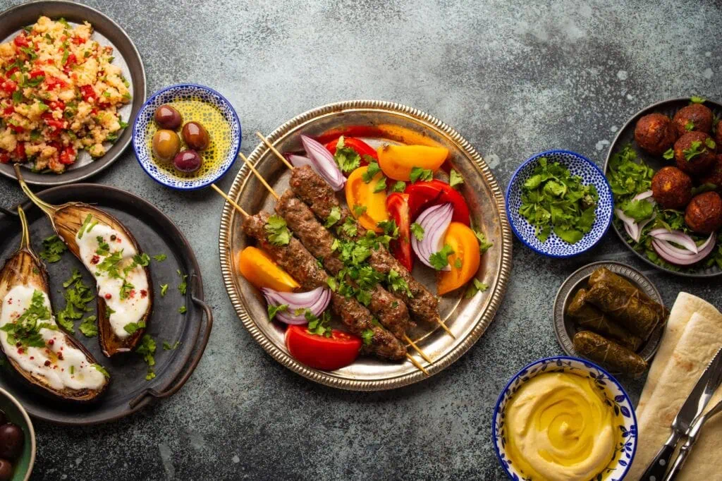 Assorted Middle Eastern food with meat kebabs, vegetable salad, and traditional meze dishes