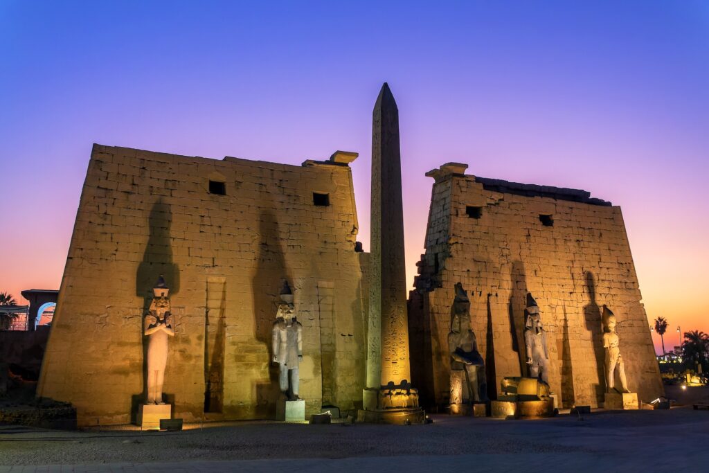 Illuminated facade of Luxor Temple with its ancient obelisk at night