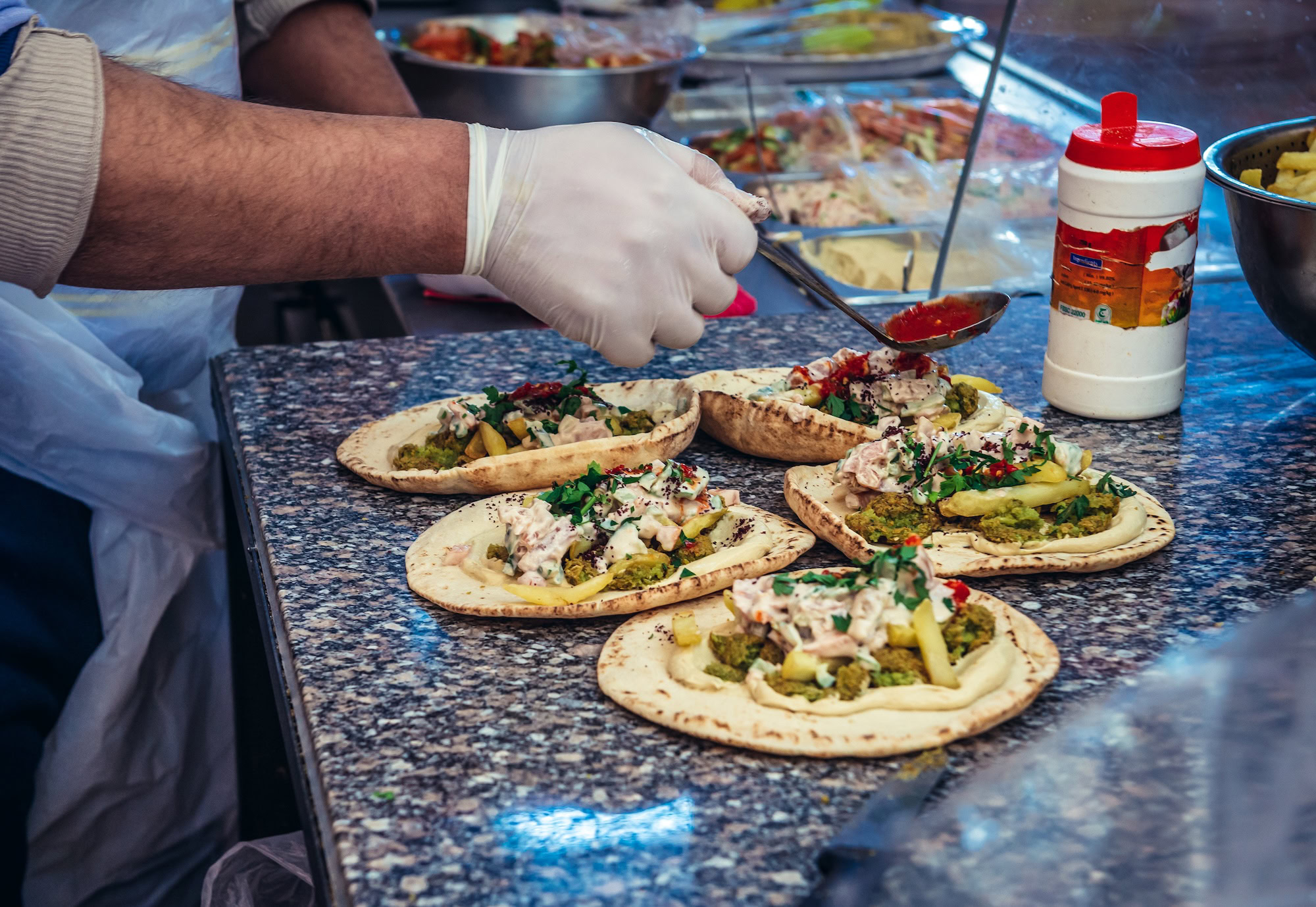 Venditore ambulante che prepara cibo di strada con pane pita e hummus