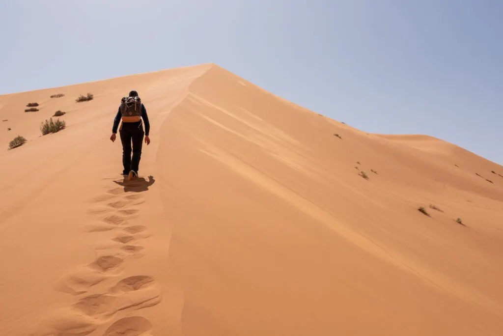 Great Dune of Merzouga with a person hiking up the steep sandy slope of Erg Chebbi surrounded by expansive desert landscape, Merzouga