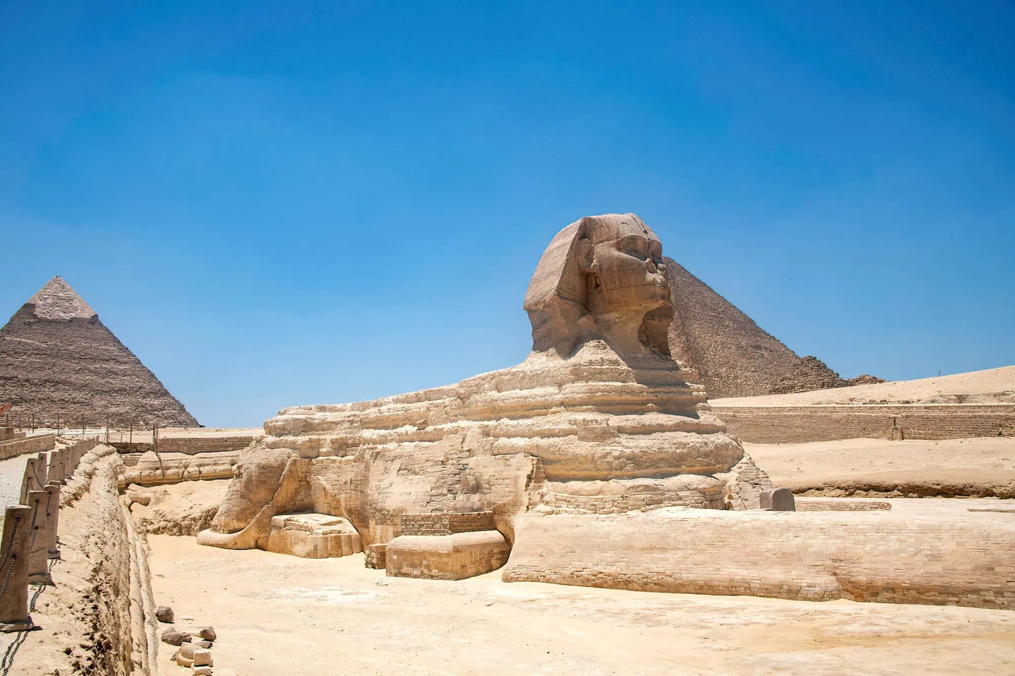 A Grande Esfinge de Gizé com pirâmide ao fundo no sítio arqueológico
