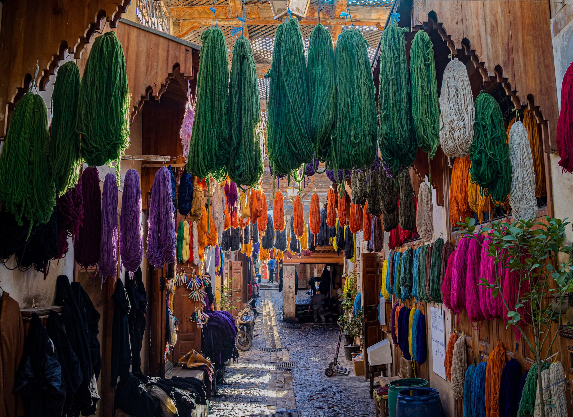Vibrant Moroccan souk with colorful textiles and yarn hanging in traditional marketplace