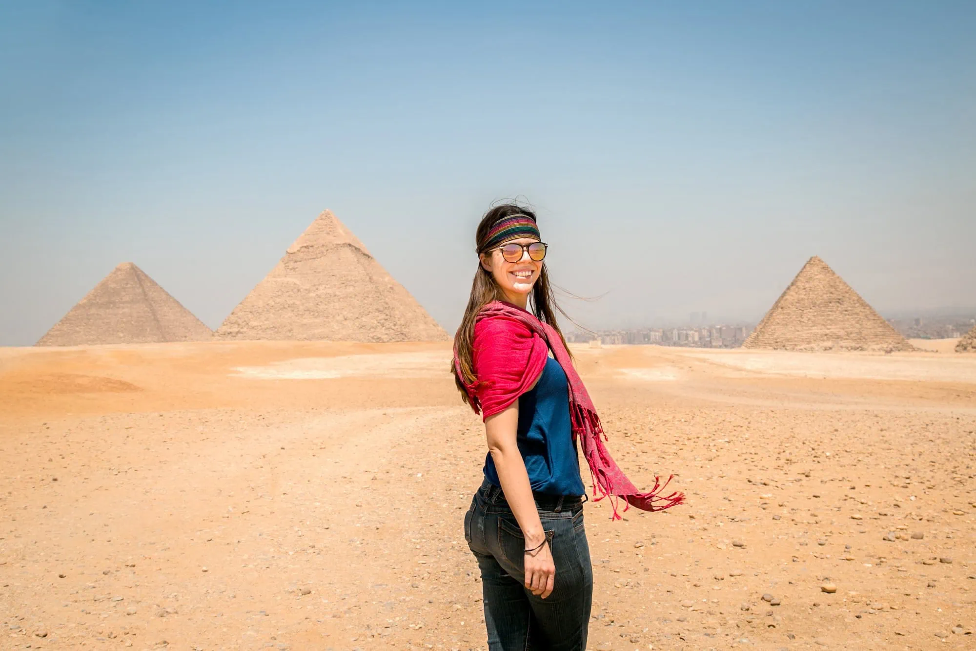 Turista con gafas de sol y pañuelo visitando las Grandes Pirámides de Giza en Egipto