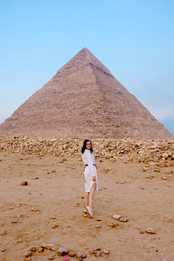 Woman standing in front of the pyramids on the desert plateau during a tourist visit, Giza