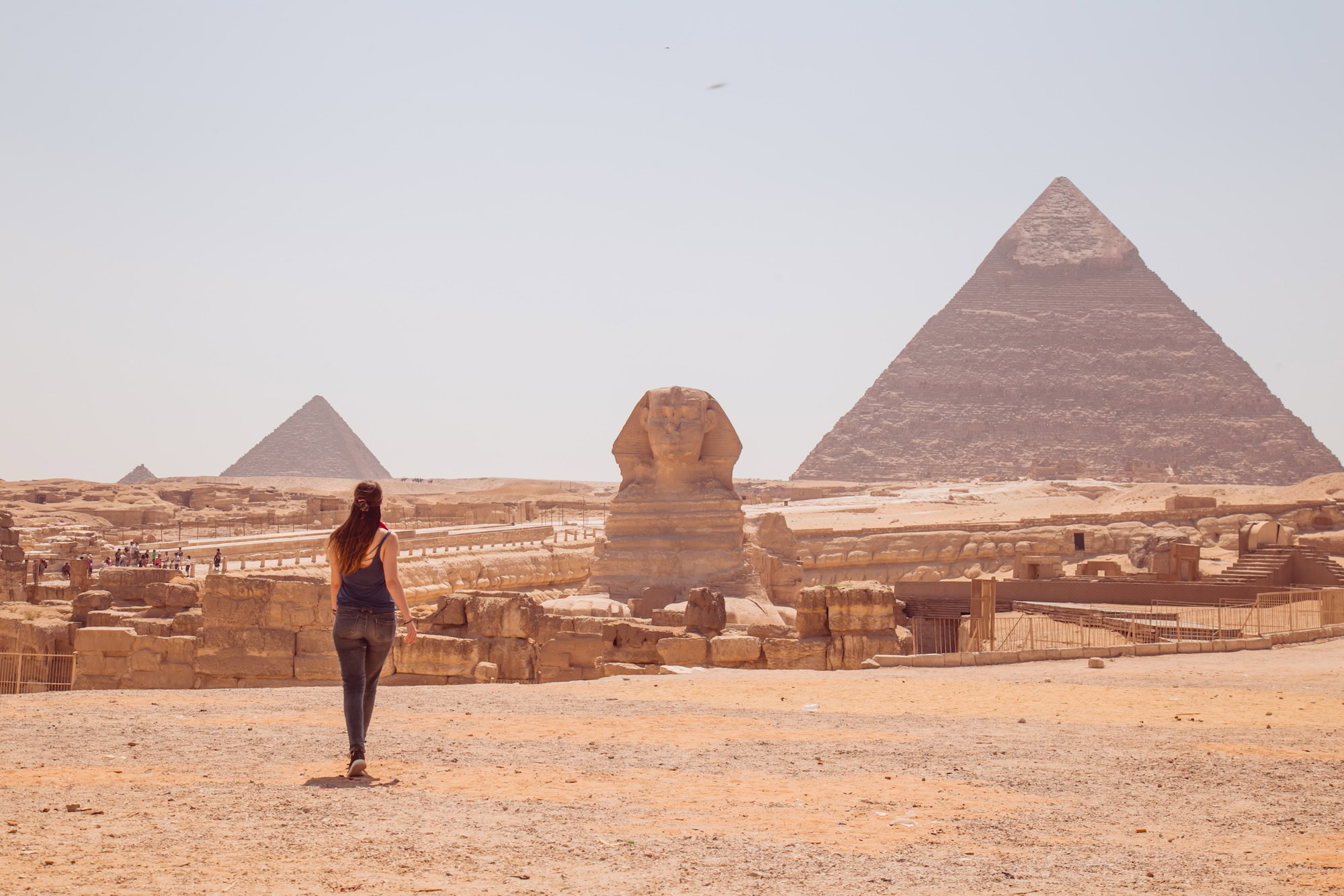Great Sphinx and pyramid with visitor walking among ancient ruins at Giza