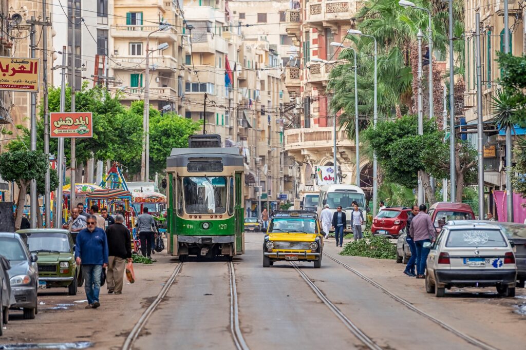 Alexandria’s vibrant streets filled with people, trams, and vintage cars