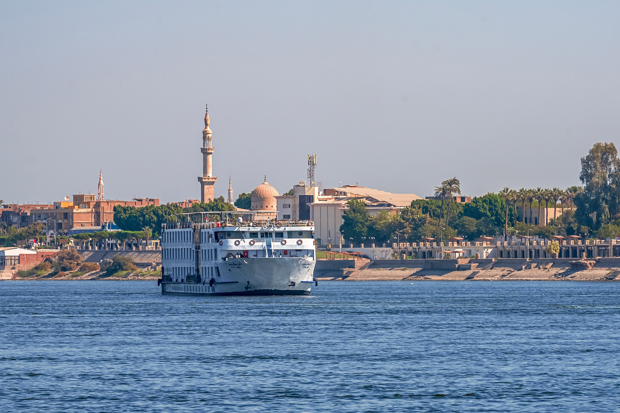 Cruise ship sailing on the Nile River near waterfront buildings