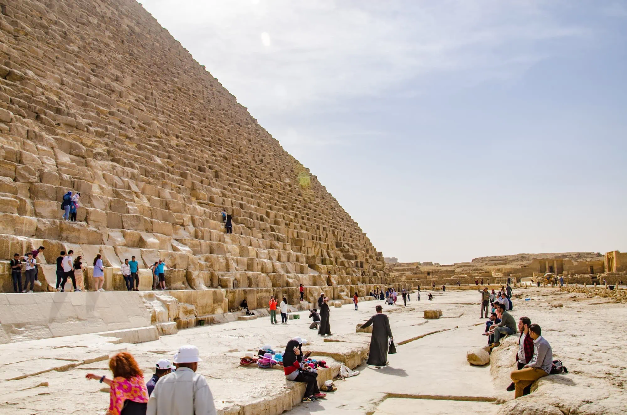 Tourists exploring the Great Pyramid of Giza with ancient limestone blocks