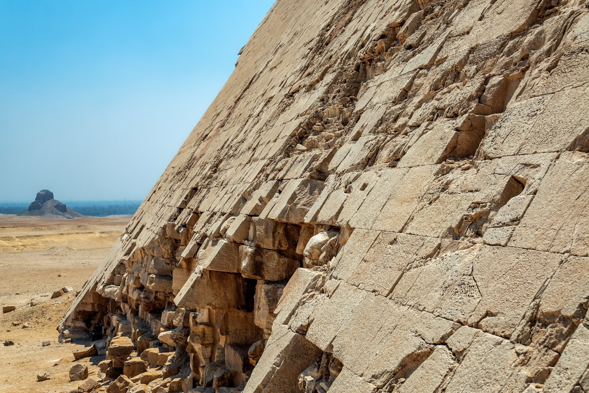 Ancient Egyptian pyramid with limestone blocks against desert landscape