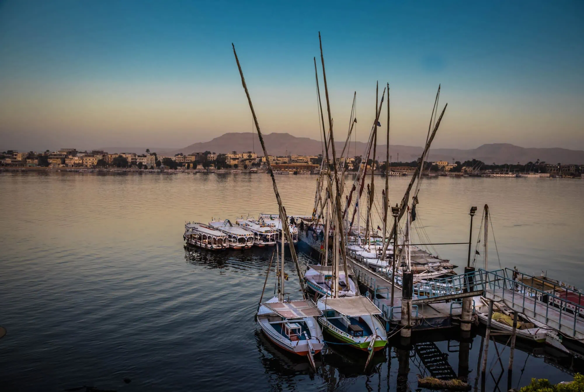Traditional felucca sailboats on the Nile River with mountains in background